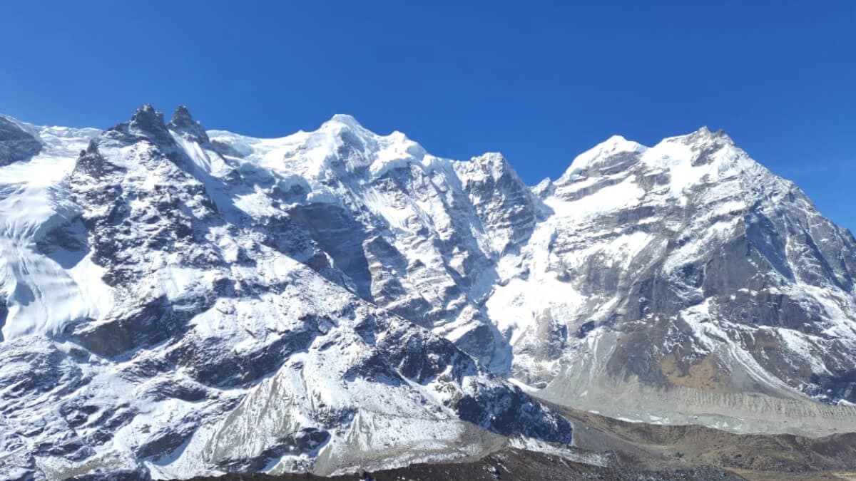 Trekking group resting at a high camp on the trail to Mera Peak, tents pitched on rocky terrain, with sweeping mountain vistas in the distance