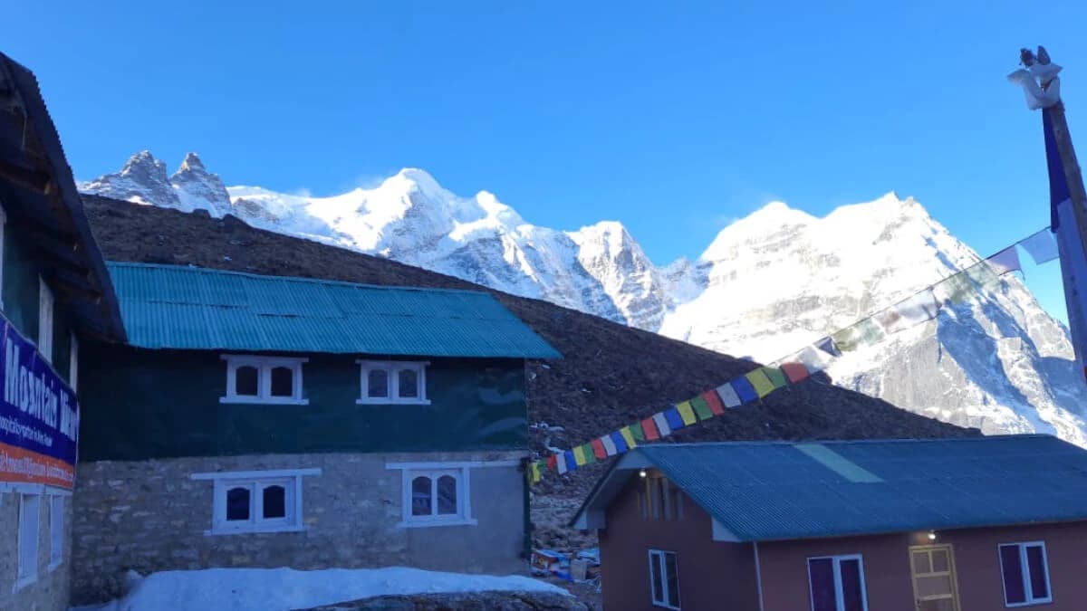 Panoramic view of Mera Peak’s summit bathed in golden sunlight, surrounded by rugged snow‑covered mountains under clear blue sky.